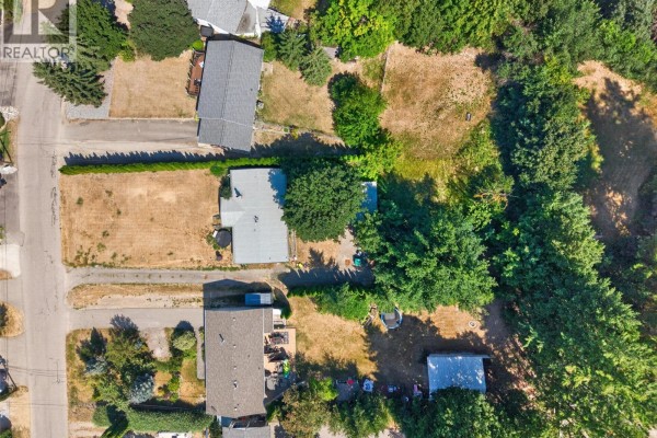 Aerial view of a single-story house on a residential street with mature trees. - 1260 16 Street Ne, Salmon Arm