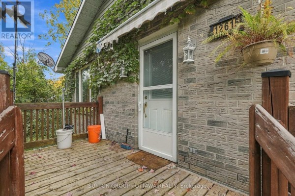 Close-up of the front door with address number 12615, surrounded by brick and ivy. - 12615 County 28 Road, South Dundas