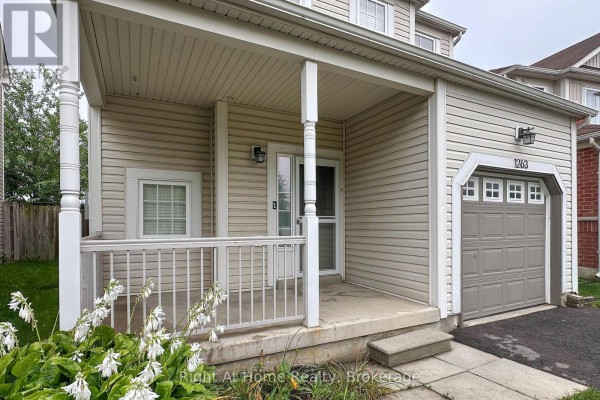 Close-up of the covered front porch and garage entrance of a beige house. - 1263 Gyatt Crescent, Oshawa