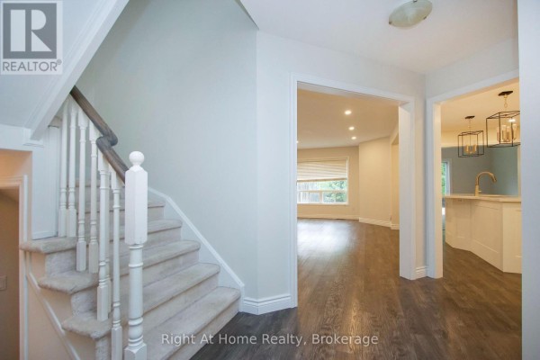 View of the entryway staircase, dark wood flooring, and open doorways to living and kitchen areas. - 1263 Gyatt Crescent, Oshawa