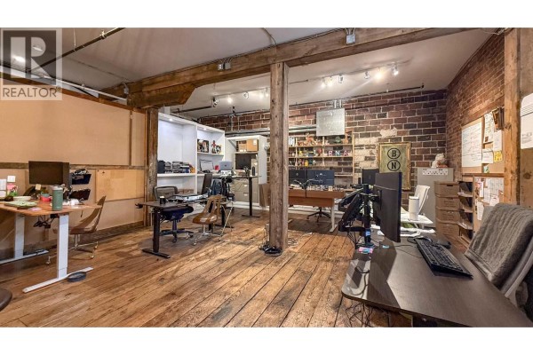 Interior office space with hardwood floors, exposed brick, and wooden support beams. - 1264 Ellis Street Unit# B, Kelowna