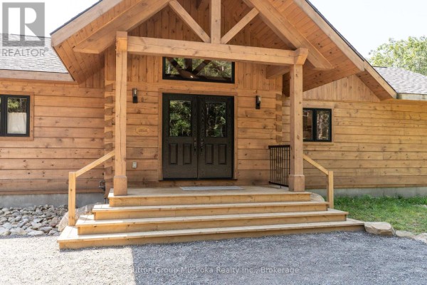 Close-up of the double front doors and wooden porch steps with timber framing overhead. - 1265 Britannia Road, Huntsville