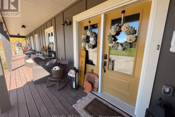 Front porch with a rocking chair, pumpkins, and a yellow double door with wreaths. - 1267 4 & 5 Concession, Cochrane