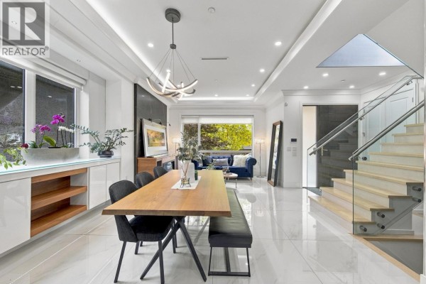 Dining area with a wooden table and benches, leading to a living room and staircase. - 1267 E 53rd Avenue, Vancouver