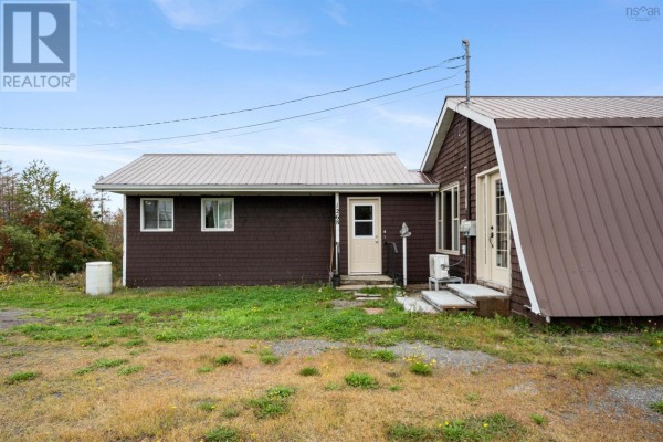 Close-up of the duplex entrance with brown siding, a light beige door, and white trim. - 1268 Plains Road, Debert