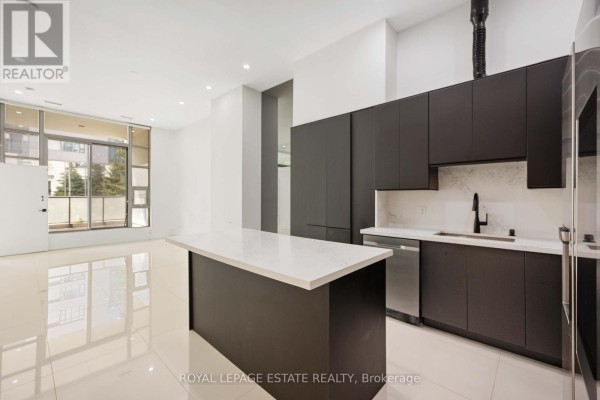 Open concept living area with modern dark cabinets, white quartz island, and patio door. - 127 - 637 Lake Shore Boulevard W, Toronto