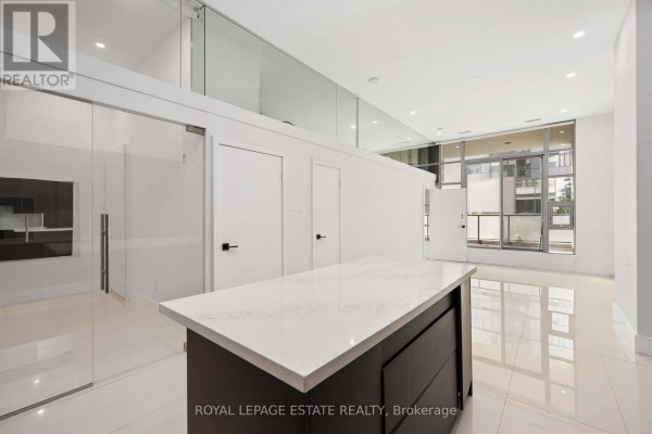 View from kitchen island showing glass partition, white doors, and city view through window. - 127 - 637 Lake Shore Boulevard W, Toronto