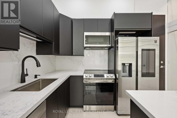 Close-up of modern kitchen with dark cabinets, stainless steel appliances, and white quartz countertops. - 127 - 637 Lake Shore Boulevard W, Toronto