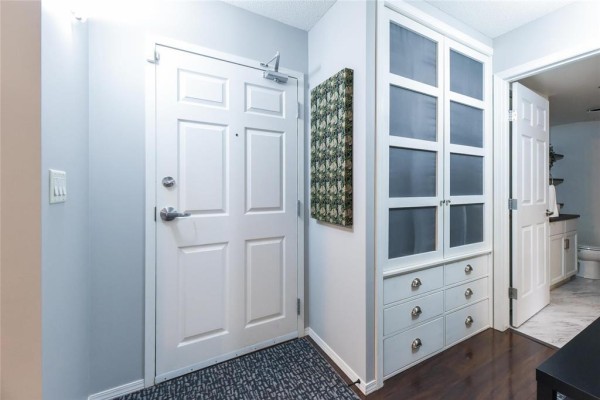 Apartment entrance with white door, built-in storage cabinets, and art on wall. - 127 230 Fairhaven Road, Winnipeg