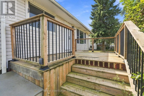 Empty wooden deck with stairs and black metal railings attached to a house. - 127 Coleman Crescent, Scugog
