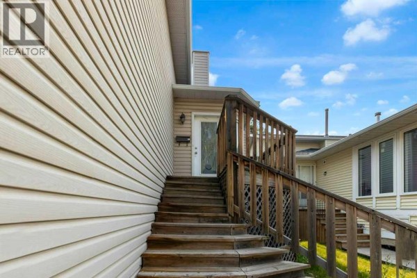 Wooden stairs with a wooden railing leading up to the front door. - 127 Scenic Cove Circle Nw, Calgary