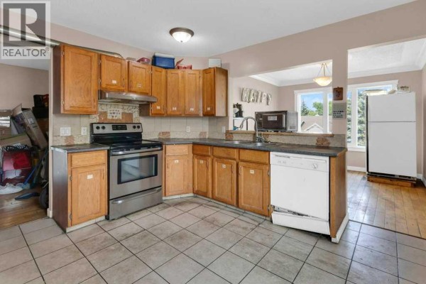 Kitchen with light wood cabinets, stainless steel appliances, and tile flooring. - 127 Scenic Cove Circle Nw, Calgary
