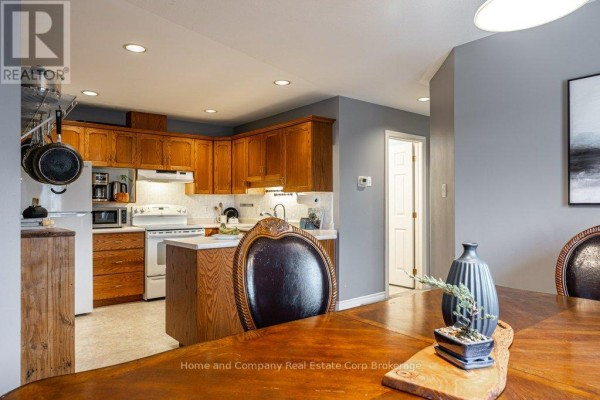 Kitchen island with wood cabinets and stainless steel dishwasher next to dining table - 127 Walsh Crescent Stratford