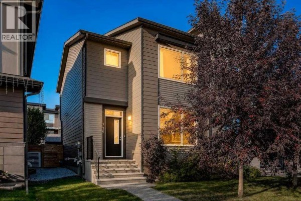 Front exterior of a modern grey duplex with a black front door and steps leading to the entrance. - 1270 Walden Drive Se, Calgary
