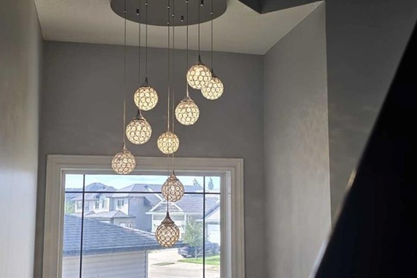 Dining area with white chairs around glass table, white cabinet, and dark curtains on large window with patio door. - 12709 105 St, Grande Prairie