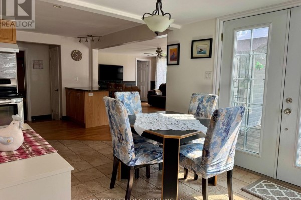Dining area with tiled floor, four upholstered chairs, and view into kitchen and living room. - 1272 Lakeshore Road, Temiskaming Shores