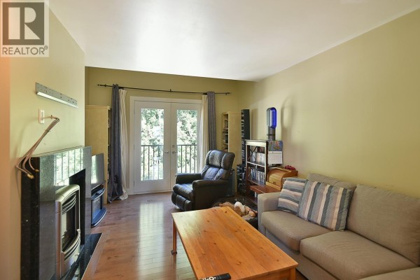 Living room with fireplace, sofa, recliner, coffee table, and double doors leading to a balcony. - 12753 Gulfview Road, Madeira Park