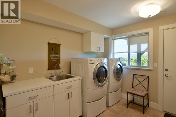 Laundry room with washer, dryer, sink, ample counter space, and a window with an ocean view. - 12753 Gulfview Road, Madeira Park