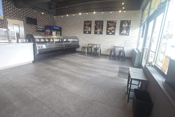 Interior view of a restaurant with a large display cooler, cafe tables, and windows. - 12760 Hwy 50 A2 Highway, Caledon