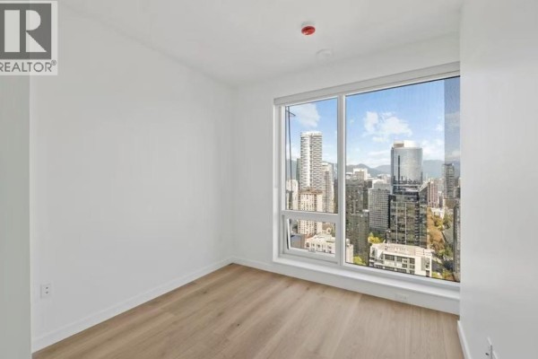 Empty room with a large window showing a panoramic view of the Vancouver cityscape and mountains. - 1277 Hornby Street, Vancouver