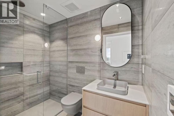 Contemporary bathroom with a glass-enclosed shower, grey tiled walls, and a light wood vanity. - 1277 Hornby Street, Vancouver