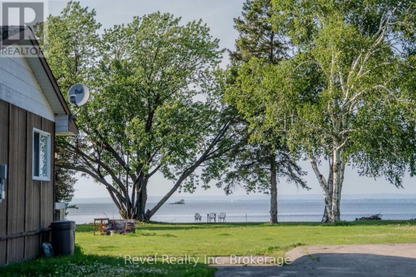 Close-up view of the side of a small building with a window, overlooking a grassy lawn with trees and a distant lake view. - 1278 Highway 654 Highway W, Callander