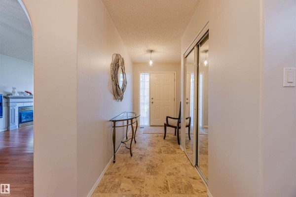 Interior view of a duplex entryway with tiled floors, a glass console table, and a closet. - #128 215 Blackburn East Dr Sw, Edmonton
