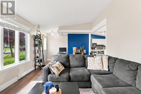 Living room with large windows and a view to the kitchen area. - 128 Boehmer Blvd, Sault Ste  Marie