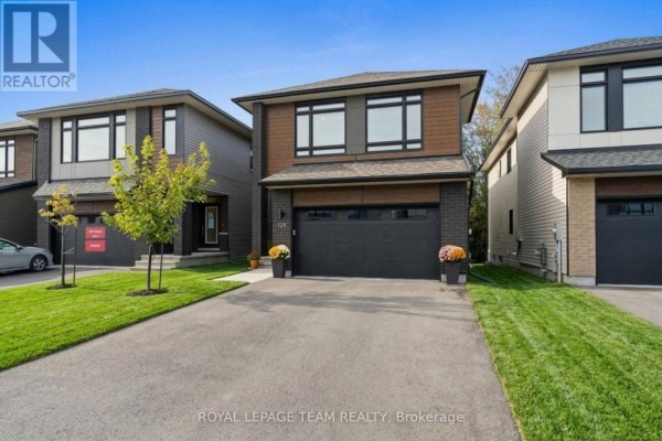 Front exterior of a modern detached home with dark brick and wood accents, a black garage door, and manicured landscaping. - 128 Bristol Crescent, North Grenville