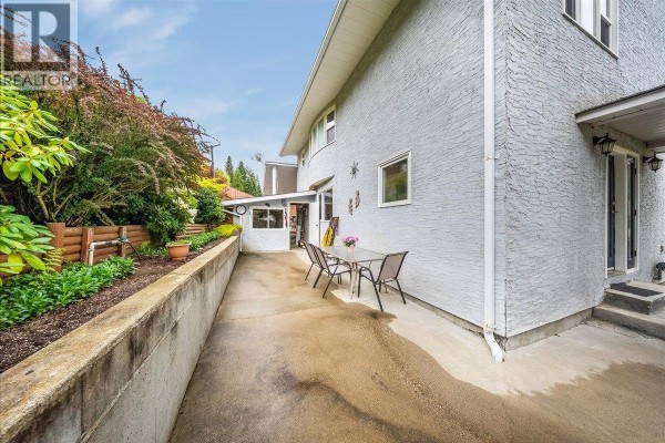 Side yard with a concrete walkway, retaining wall, and outdoor dining set. - 128 Colley Street, Warfield