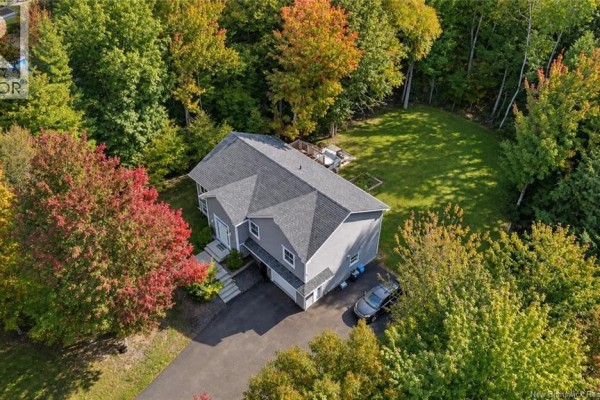 Aerial view of a grey house with a grey roof surrounded by mature trees and a green lawn. - 128 Country Wood Lane, Richibucto Road
