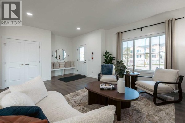 Open-concept living and dining area with fireplace, sofa, and kitchen island. - 128 Heartland Street, Cochrane