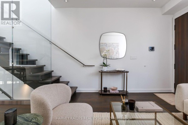 Living room area with a floating staircase, marble console table, and modern art. - 128 Montgomery Avenue, Toronto