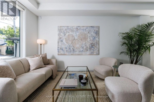 Living room with a large sectional sofa, glass coffee table, and abstract wall art. - 128 Montgomery Avenue, Toronto