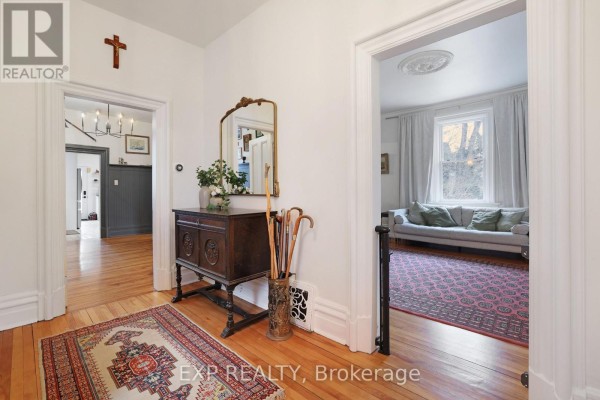 Living room with floor-to-ceiling bookshelves, leather sofa, and chaise lounge. - 128 Renfrew Avenue E, Renfrew