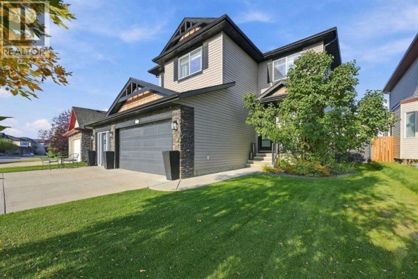 Side view of a two-story house with a double garage and well-maintained lawn. - 128 Seagreen Way, Chestermere