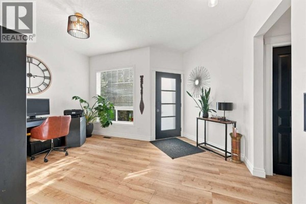 Interior view of a bright entryway with a desk, plants, and a glass door. - 128 Seagreen Way, Chestermere