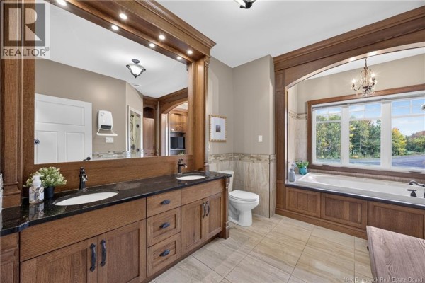 A bathroom with a double vanity, soaking tub, and large window with a scenic view. - 128 Slipp Drive, Mazerolle Settlement