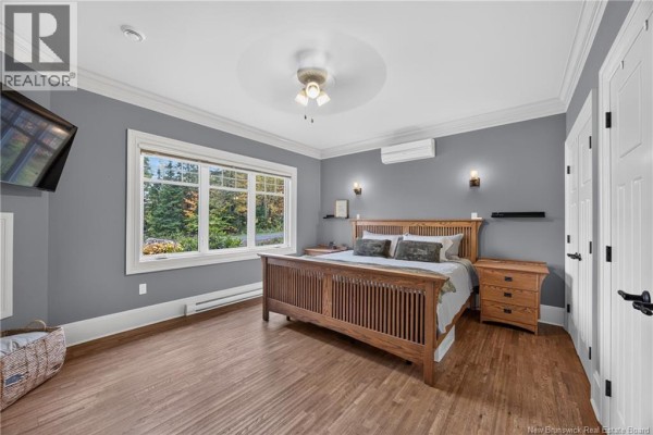 A bedroom with a wooden bed frame, nightstands, and a large window overlooking the trees. - 128 Slipp Drive, Mazerolle Settlement