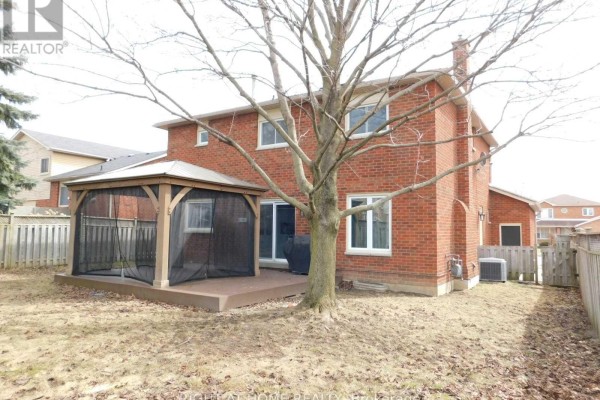 Rear view of the house showing a wooden deck with a screened gazebo, and a backyard with a fence. - 128 William Stephenson Drive, Whitby