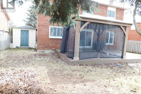 View of the backyard with a shed, deck, and screened gazebo, surrounded by a wooden fence. - 128 William Stephenson Drive, Whitby