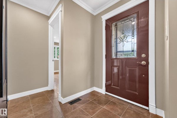 Front entry door with glass insert and adjacent hallway leading into the home. - 12819 45 St Nw, Edmonton