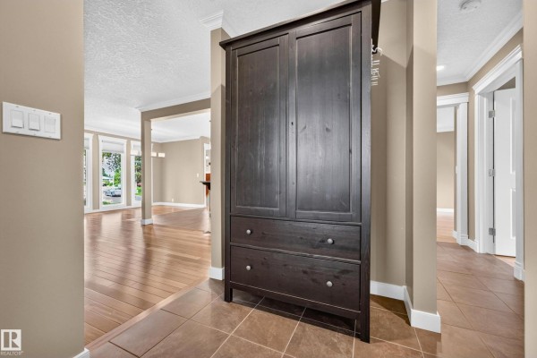 Foyer area with a dark wood storage cabinet and doorways to living spaces. - 12819 45 St Nw, Edmonton