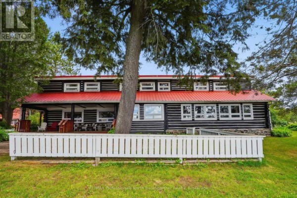 Exterior view of a log cabin with a red metal roof and a white picket fence in front. - 1282 Carroll Road, Dysart Et Al