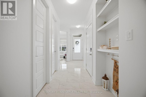 Hallway looking towards the front door, with white panel doors and a built-in shelf unit. - 1282 Stirling Todd Terrace, Milton