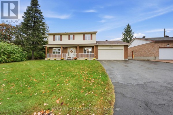 Side exterior view of a two-story beige house with a brick base and a white porch. - 1283 Surrey Avenue, Ottawa