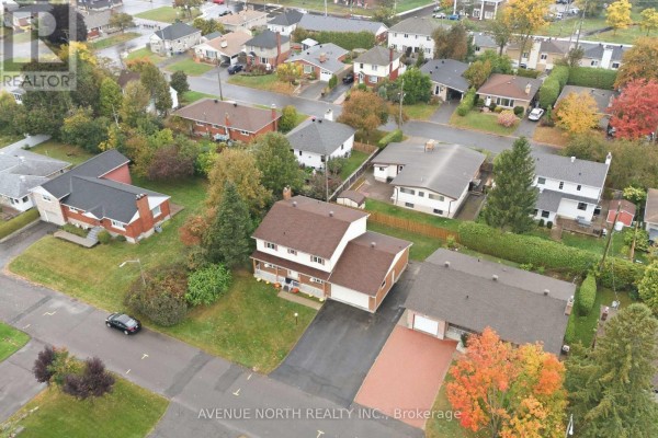 Aerial view of the neighborhood showing multiple houses with surrounding trees in autumn colors. - 1283 Surrey Avenue, Ottawa