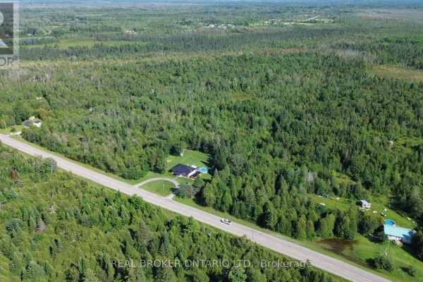 Aerial view of the property showing multiple buildings, a pool, and extensive woodland. - 12830 County  15 Road, Merrickville Wolford