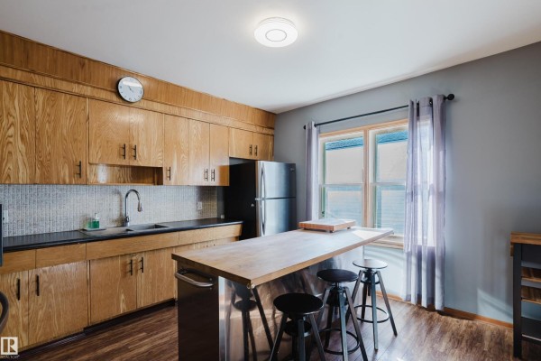 Kitchen with light wood cabinets, a stainless steel refrigerator, and a butcher block island. - 12831 126 St Nw, Edmonton