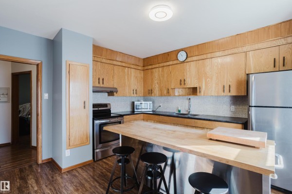Kitchen with light wood cabinets, a stainless steel stove, and a gray countertop. - 12831 126 St Nw, Edmonton